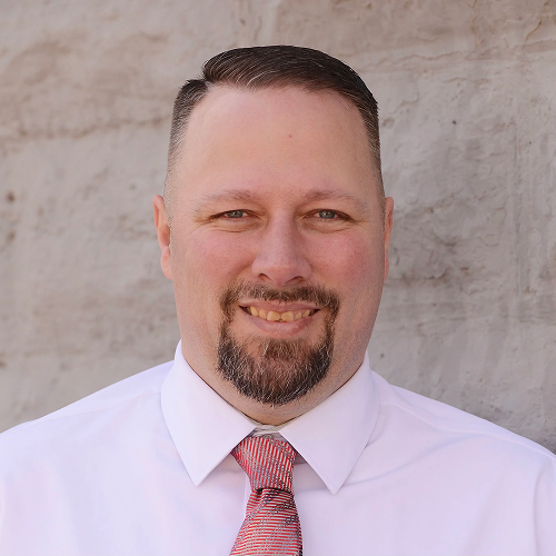 Smiling man in white shirt and tie.