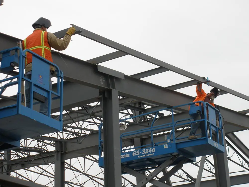 large industrial warehouse with machinery and yellow support structures under bright overhead lighting - steel structure installation stock pictures, royalty-free photos & images