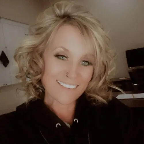 Smiling woman with curly blonde hair.