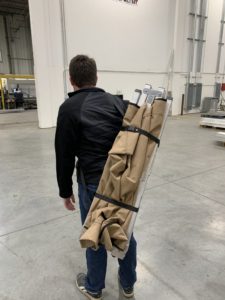 Man carrying folded tent indoors