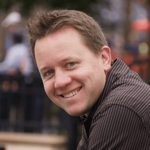 Smiling man in striped shirt outdoors.