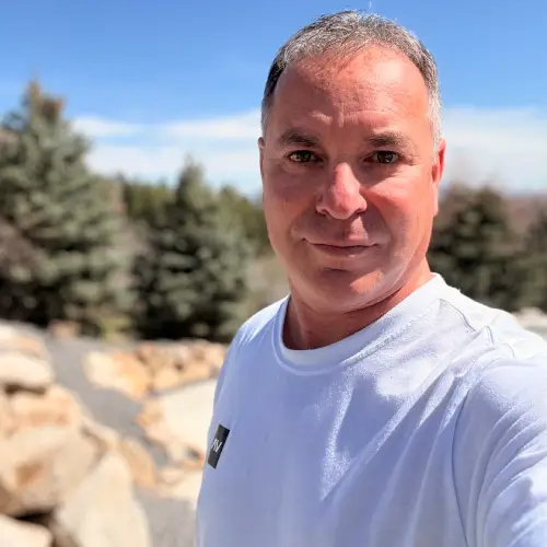 Man outdoors with trees in the background.